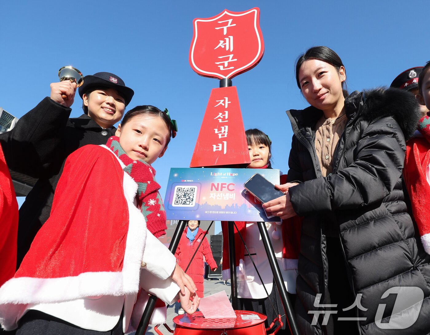 본문 이미지 - 2025 구세군 연말 모금 캠페인이 시작된 28일 오전 서울 광화문광장에서 열린 2025 구세군 자선냄비 시종식에서 서울주니어합창단 어린이들과 학부모가 NFC 모금 시연을 하고 있다. 올해로 97번째를 맞는 구세군 연말 자선냄비 모금 캠페인은 'Light of Hope'(희망의 빛)을 주제로 전국 300여 곳에서 진행된다. 올해 자선냄비에는 NFC 기반 ‘원태그 스마트기부’가 새롭게 도입돼 현금 없이도 손쉽게 참여할 수 있다. (공동취재) 2025.11.28/뉴스1 ⓒ News1 오대일 기자