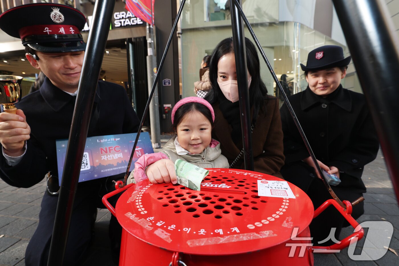 본문 이미지 - 2025 구세군 연말 모금 캠페인이 시작된 28일 오후 서울 중구 명동거리에서 한 어린이가 엄마와 함께 자선냄비에 기부하고 있다. 2025.11.28/뉴스1 ⓒ News1 오대일 기자