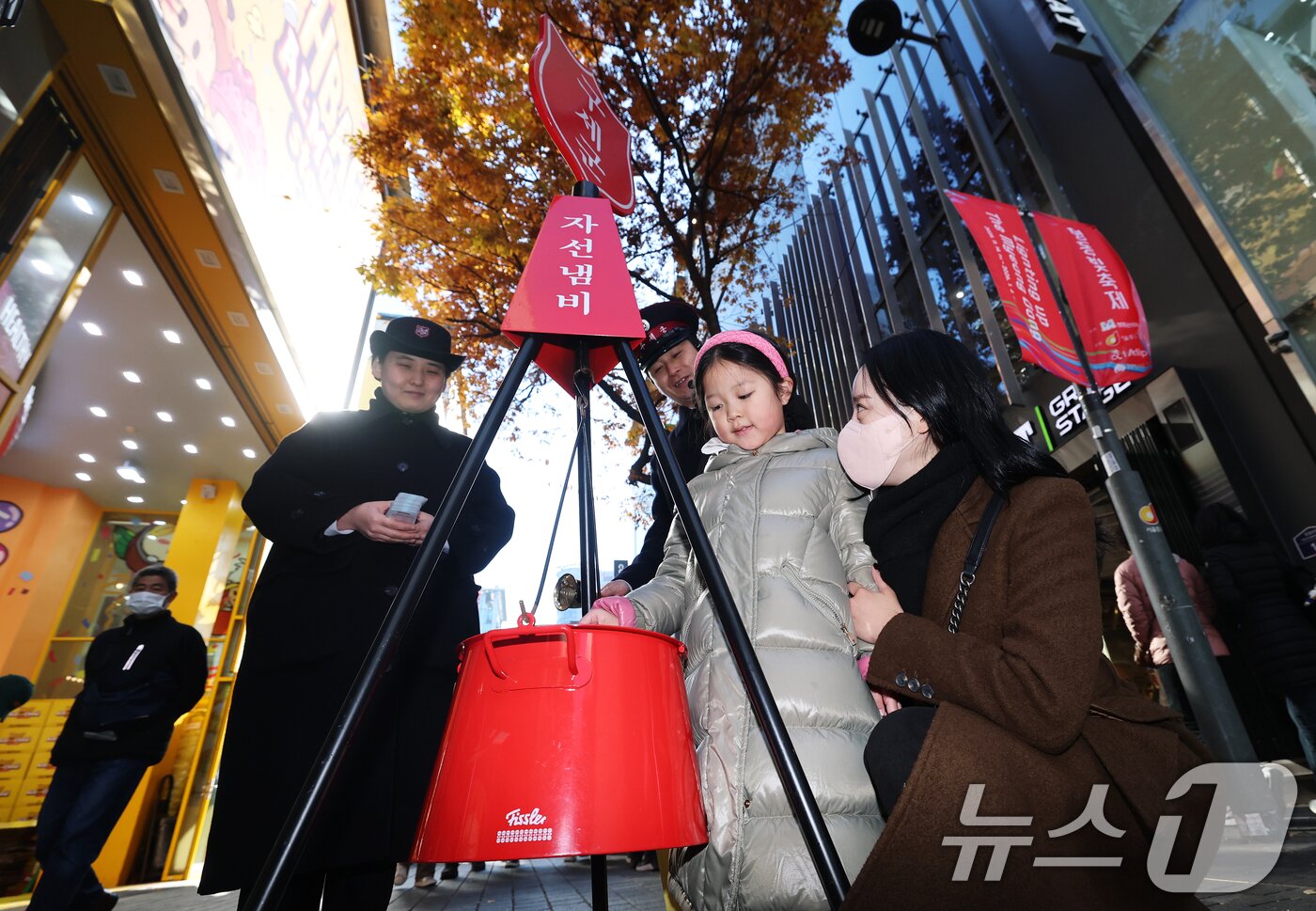 본문 이미지 - 2025 구세군 연말 모금 캠페인이 시작된 28일 오후 서울 중구 명동거리에서 한 어린이가 엄마와 함께 자선냄비에 기부하고 있다.  2025.11.28/뉴스1 ⓒ News1 오대일 기자
