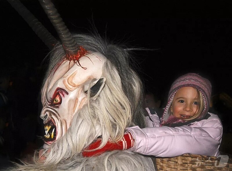 본문 이미지 - 크람푸스 분장을 한 어른에게 엎힌 아이가 활짝 웃음 짓고 있다.(오스트리아관광청 제공)