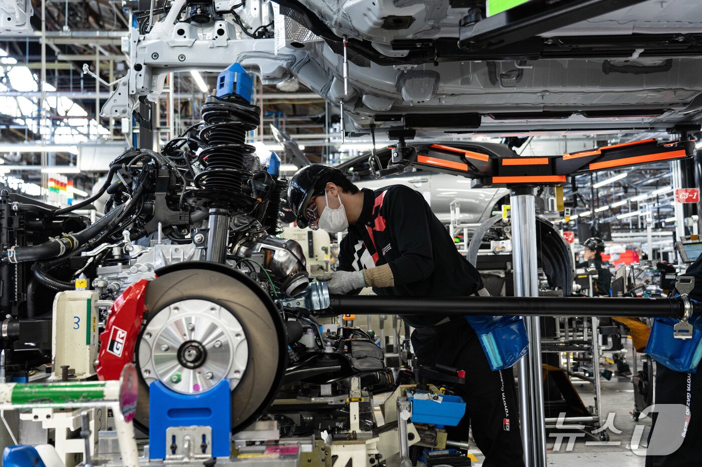 본문 이미지 - 31일 일본 아이치현 소재 도요타 GR 공장에서 작업자가 차체 하부의 구동·조향 장치를 조립하고 있다. 무인운반차(AGV)에 실린 차체는 하단에 고정된 차체 하부로 내려와 연결됐다(한국토요타자동차 제공). 2025.10.31.
