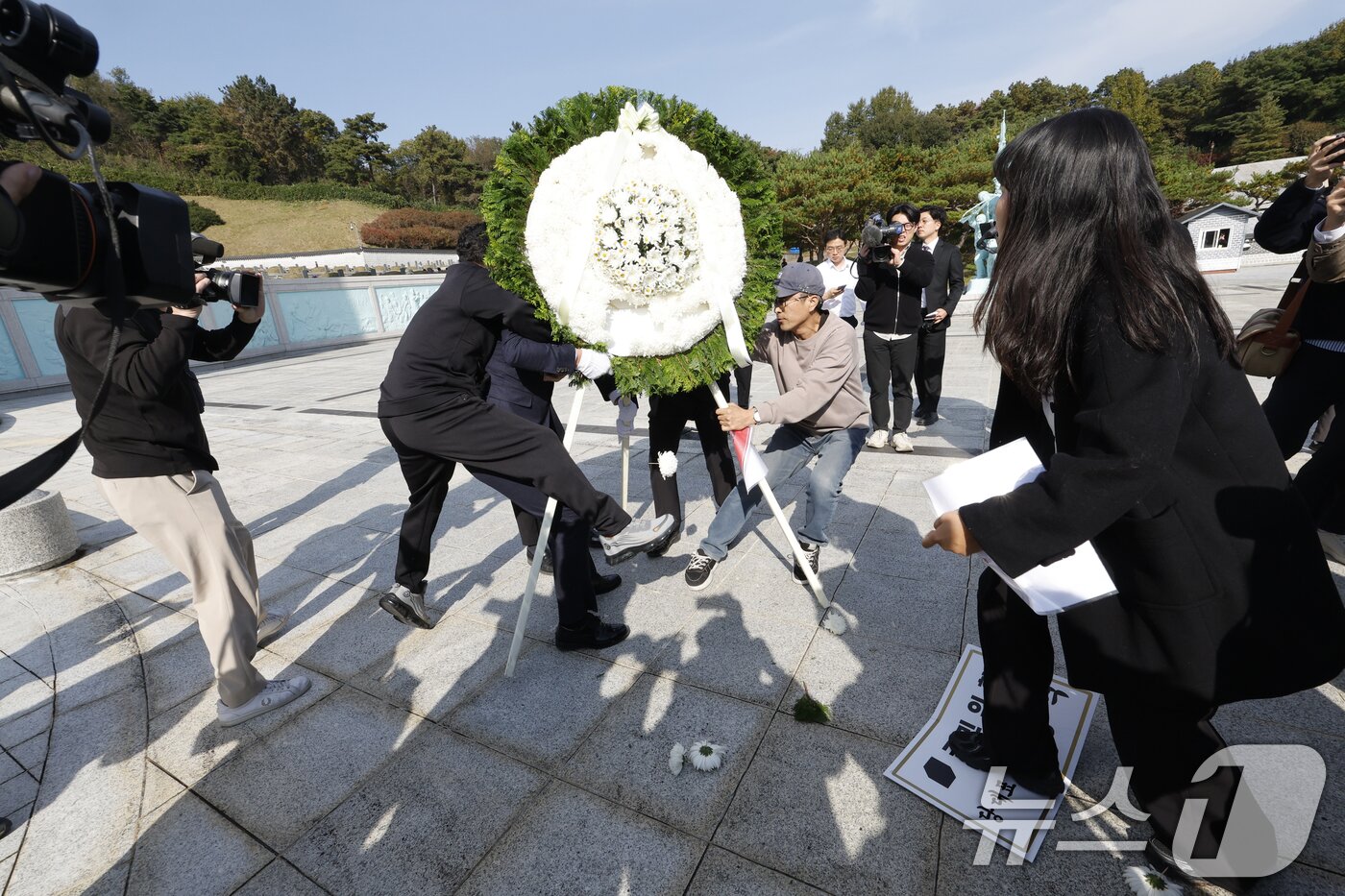 본문 이미지 - 장동혁 국민의힘 대표가 6일 광주를 찾아 국립 5·18민주묘지를 참배하기 위해 들어서자 광주전남촛불행동 회원들이 당대표 조화를 치우고 있다. 2025.11.6/뉴스1 ⓒ News1 김태성 기자