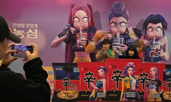 본문 이미지 - 지난 7일 경북 구미시 구미역 앞에서 열린 &#39;2025 구미라면축제&#39; 행사장을 찾은 방문객들이 넷플릭스 애니메이션 영화 &#39;케이팝 데몬 헌터스&#39; 가 라면을 먹는 모습을 배경으로 기념사진을 찍고 있다.. 2025.11.7/뉴스1 ⓒ News1 정우용 기자