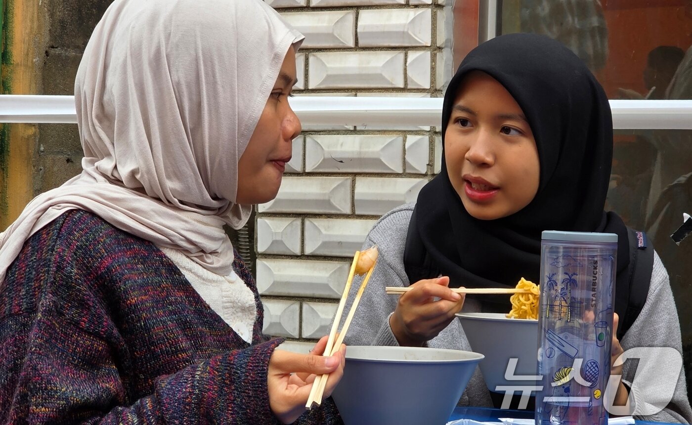 본문 이미지 - 8일 경북 구미에서 열리고 있는 '2025 구미라면축제' 행사장을 찾은 외국인 방문객이 주문한 라면을 먹으며 즐거운 시간을 보내고 있다. 라면축제는 오는 9일까지 구미역 일대에서 계속된다. 2025.11.8/뉴스1 ⓒ News1 정우용 기자