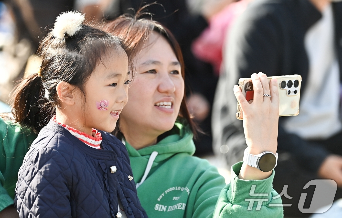 (구미=뉴스1) 정우용 기자 = 9일 구미 라면축제 연계행사로 금오산 잔디광장에서 열린 '캐치 티닝핑' 콘서트에 참여한 한 어머니가 딸과 함께 티니핑 공연을 동영상으로 찍으며 즐거 …