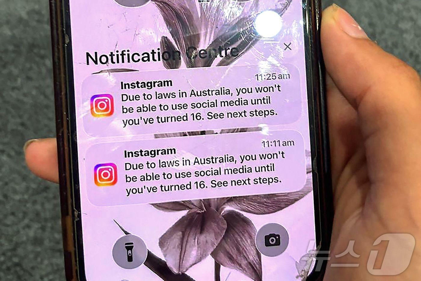 본문 이미지 - 9일 호주 시드니에서 한 10대 청소년이 소셜미디어 플랫폼 인스타그램 계정이 연령확인을 위해 잠긴 계정의 메시지가 표시된 휴대전화를 들고 있다. 2025.12.09. ⓒ AFP=뉴스1