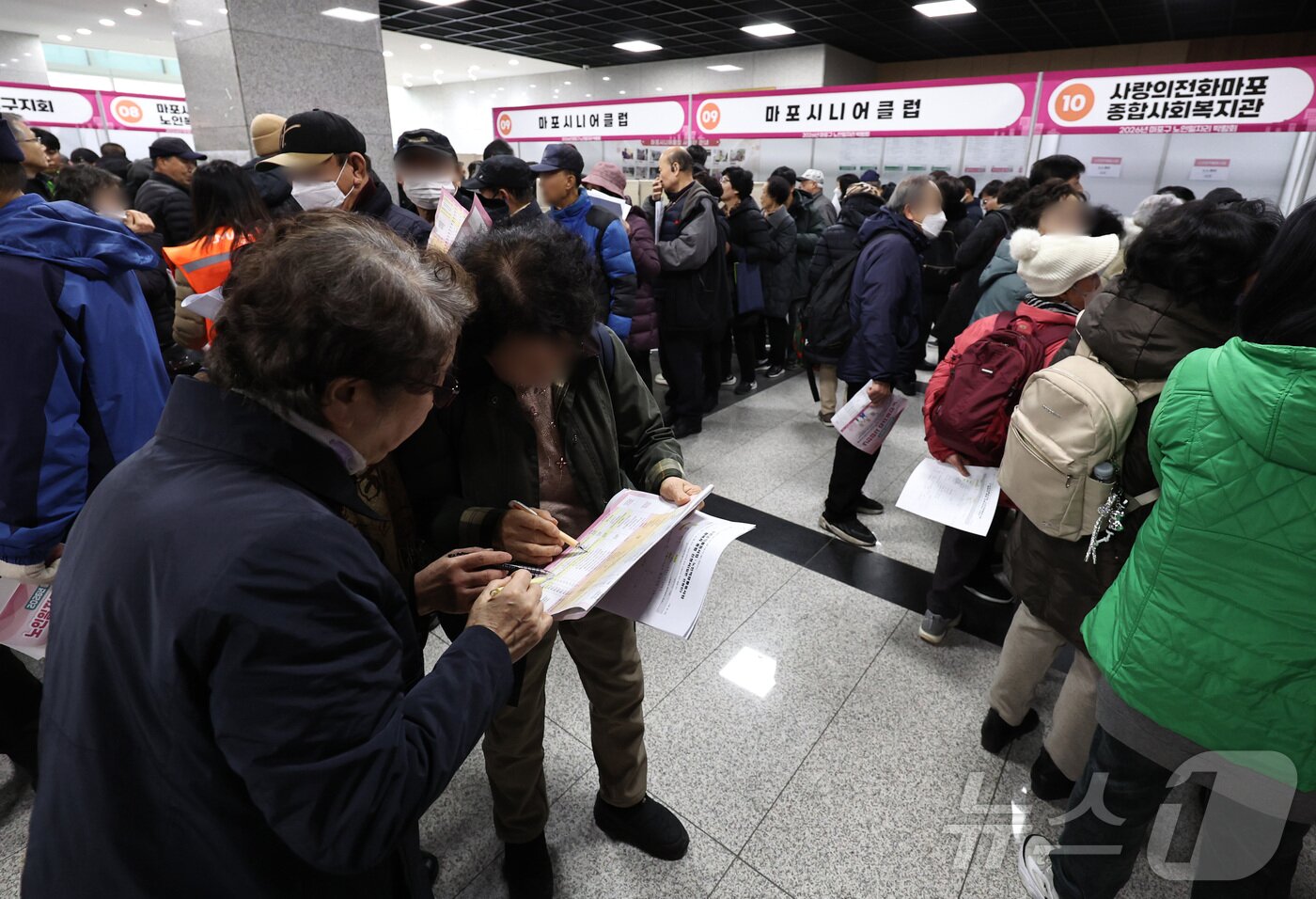 본문 이미지 - 10일 오후 서울 마포구청에서 열린 노인일자리 박람회에서 어르신들이 참가업체 모집요강을 살펴보고 있다. 2025.12.10/뉴스1 ⓒ News1 구윤성 기자