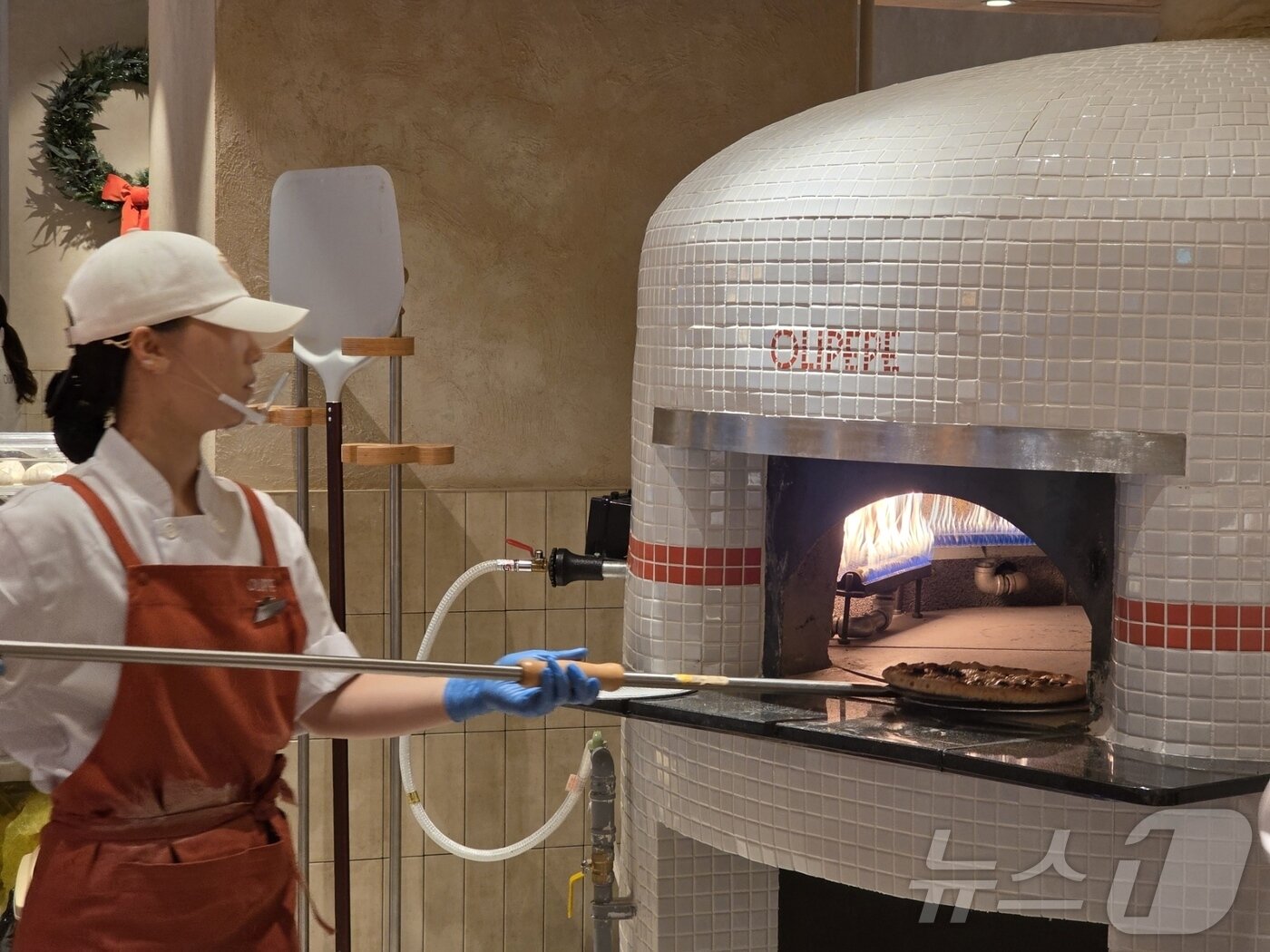 본문 이미지 - CJ푸드빌이 11일 새 외식 브랜드 올리페페를 오픈했다.  직원이 화덕에서 피자를 굽고 있다. ⓒ News1 이형진 기자