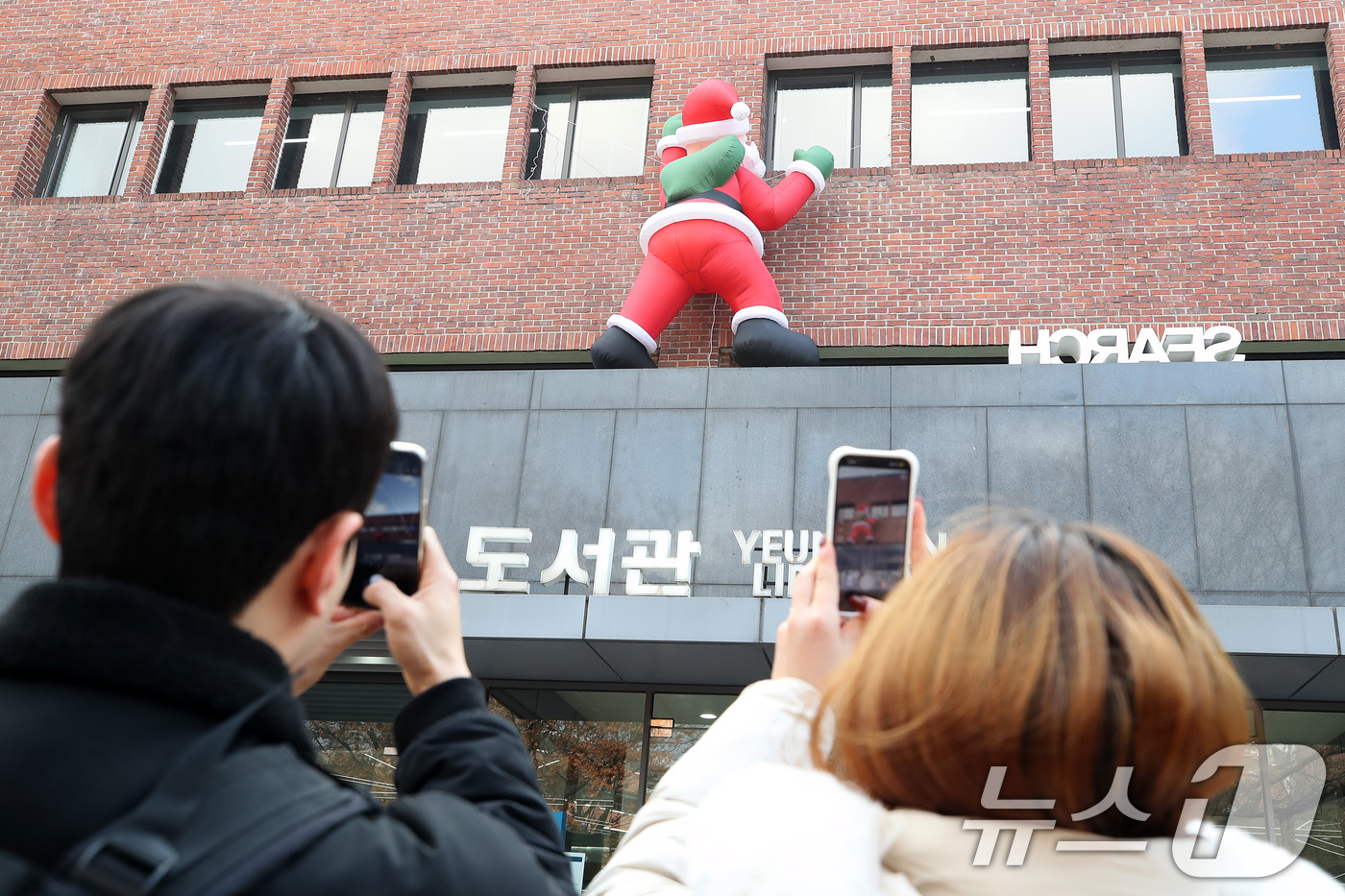 (대구=뉴스1) 공정식 기자 = 11일 오후 크리스마스를 앞두고 대구 북구 영진전문대 도서관 외벽에 설치된 산타 인형이 기말고사를 맞아 도서관을 찾는 학생들의 눈길을 끌고 있다. …