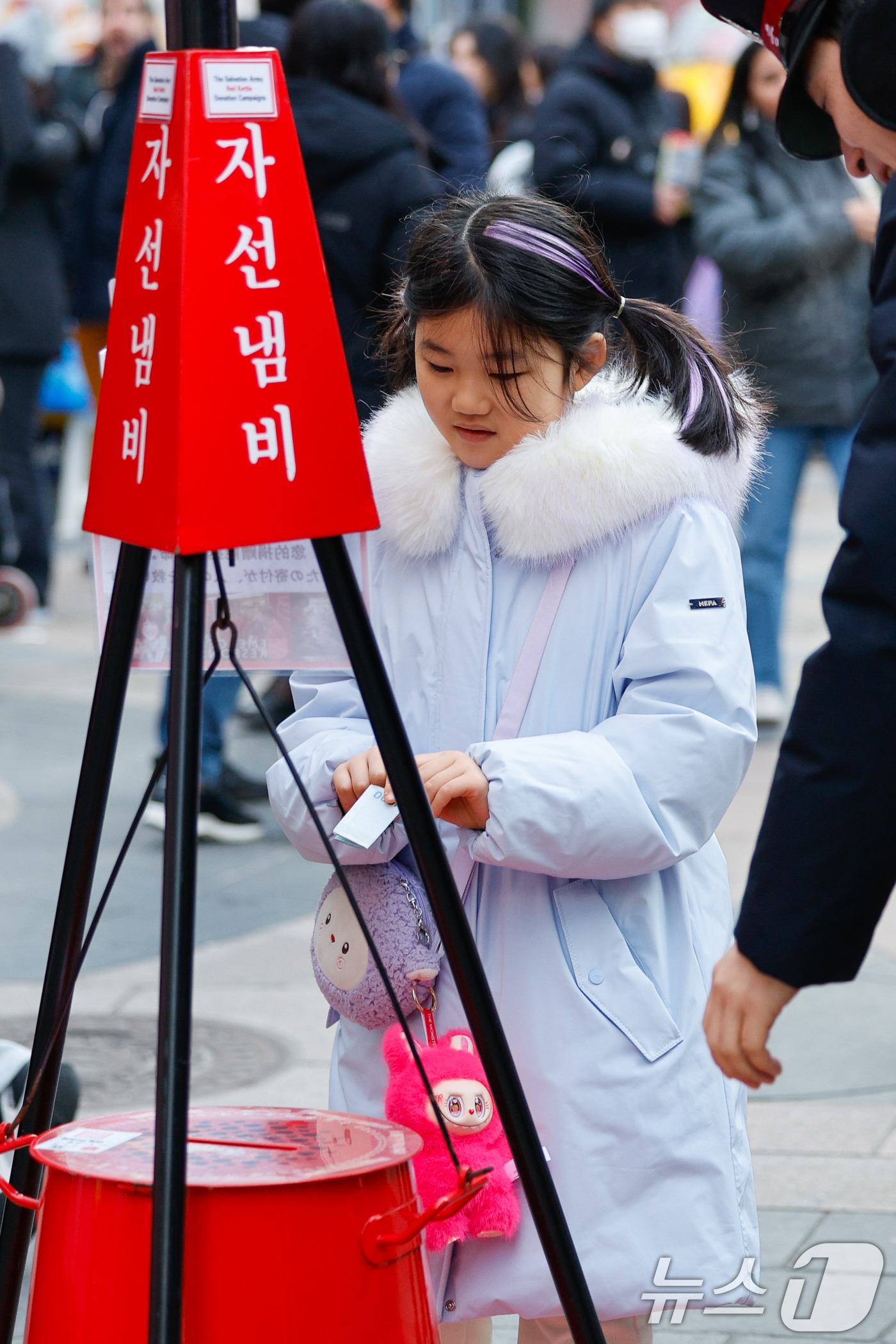(서울=뉴스1) 안은나 기자 = 14일 서울 중구 명동거리에서 한 어린이가 구세군 연말 거리모금 캠페인 자선냄비에 온정의 손길을 더하고 있다. 2025.12.14/뉴스1