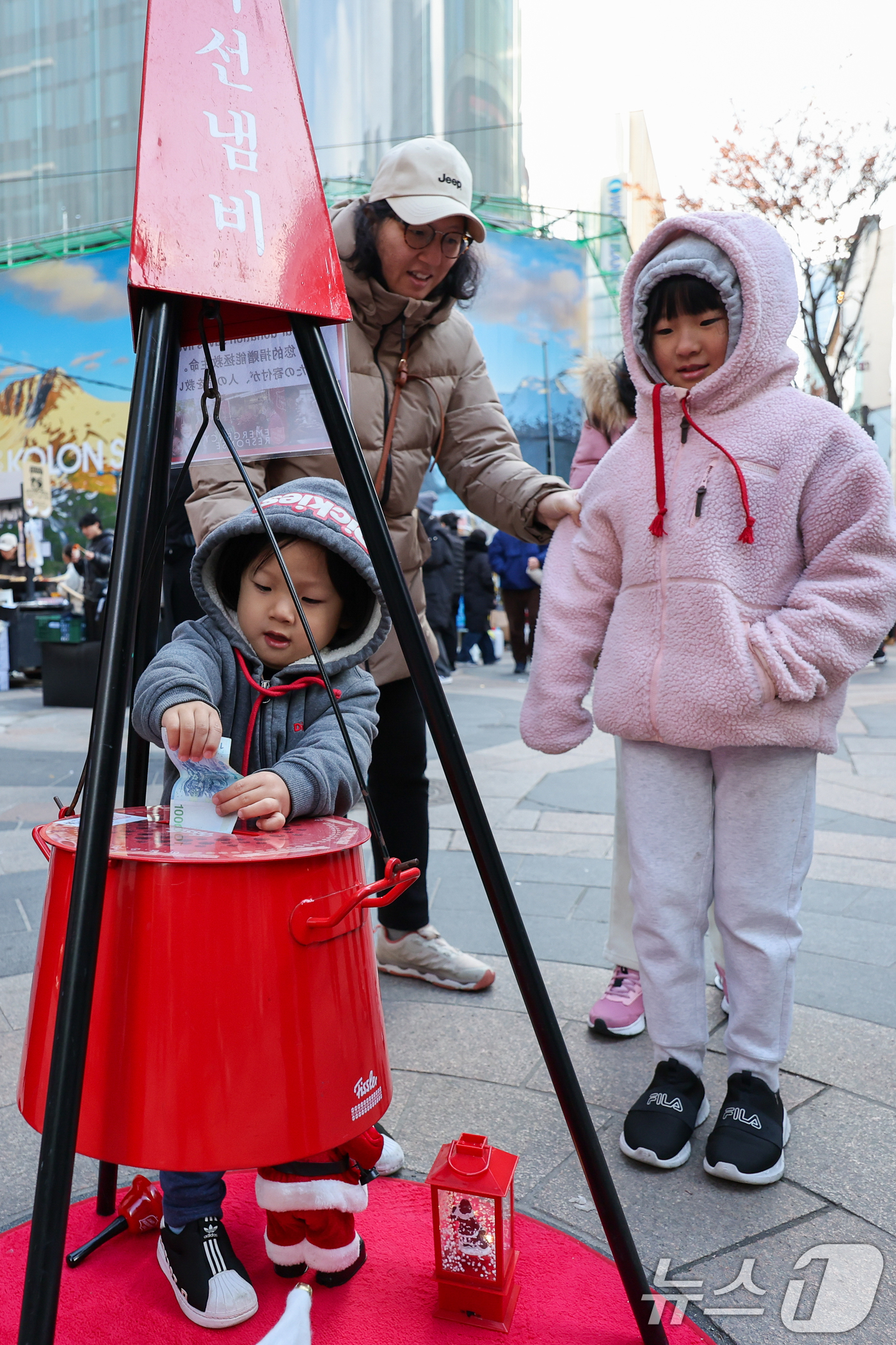 (서울=뉴스1) 안은나 기자 = 14일 서울 중구 명동거리에서 한 어린이가 구세군 연말 거리모금 캠페인 자선냄비에 온정의 손길을 더하고 있다. 2025.12.14/뉴스1