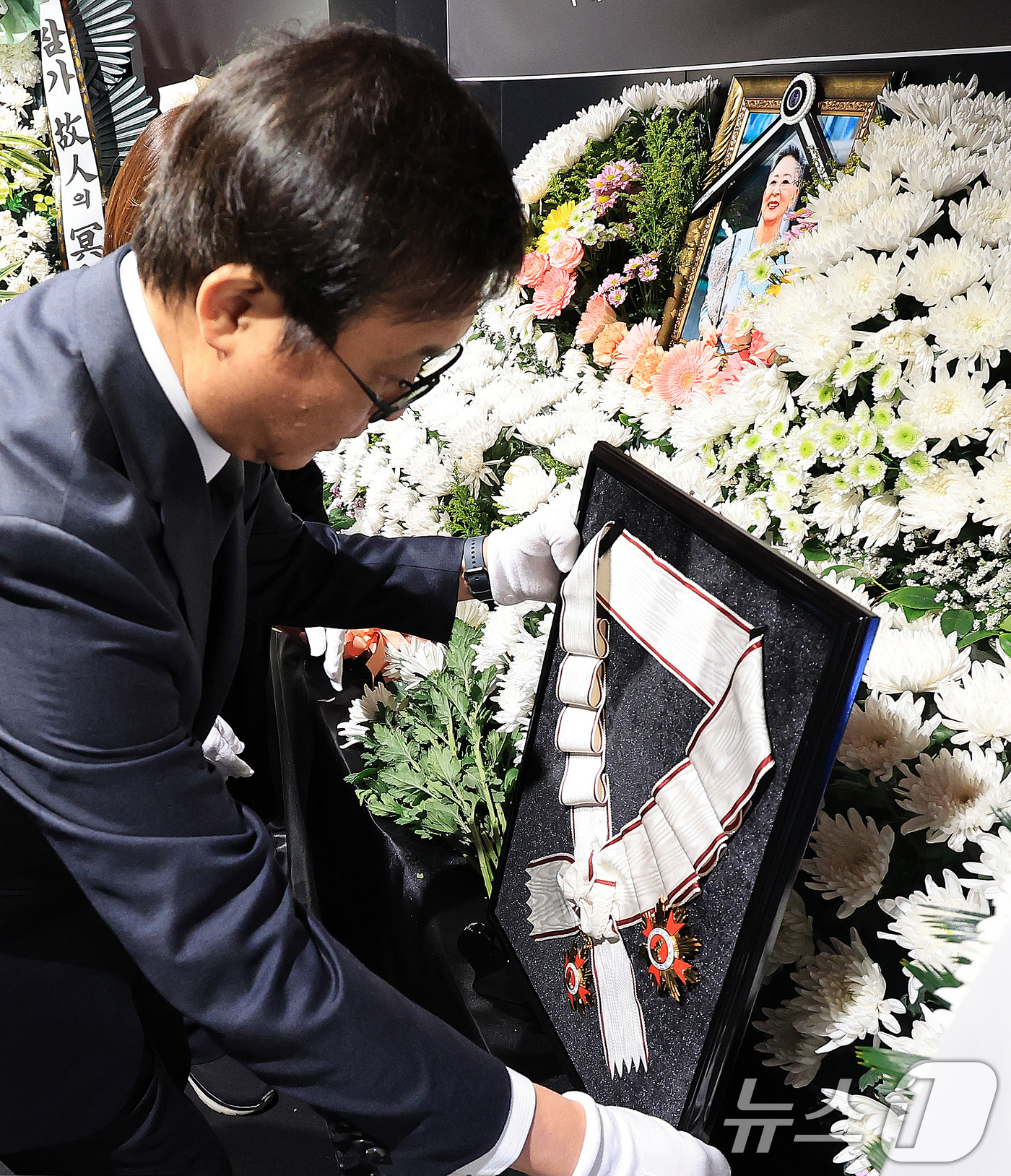 (서울=뉴스1) 이호윤 기자 = 최휘영 문화체육관광부 장관이 14일 서울 중구 서울영화센터에 마련된 고 김지미 배우의 추모공간을 찾아 금관문화훈장을 전달하고 있다. 2025.12. …