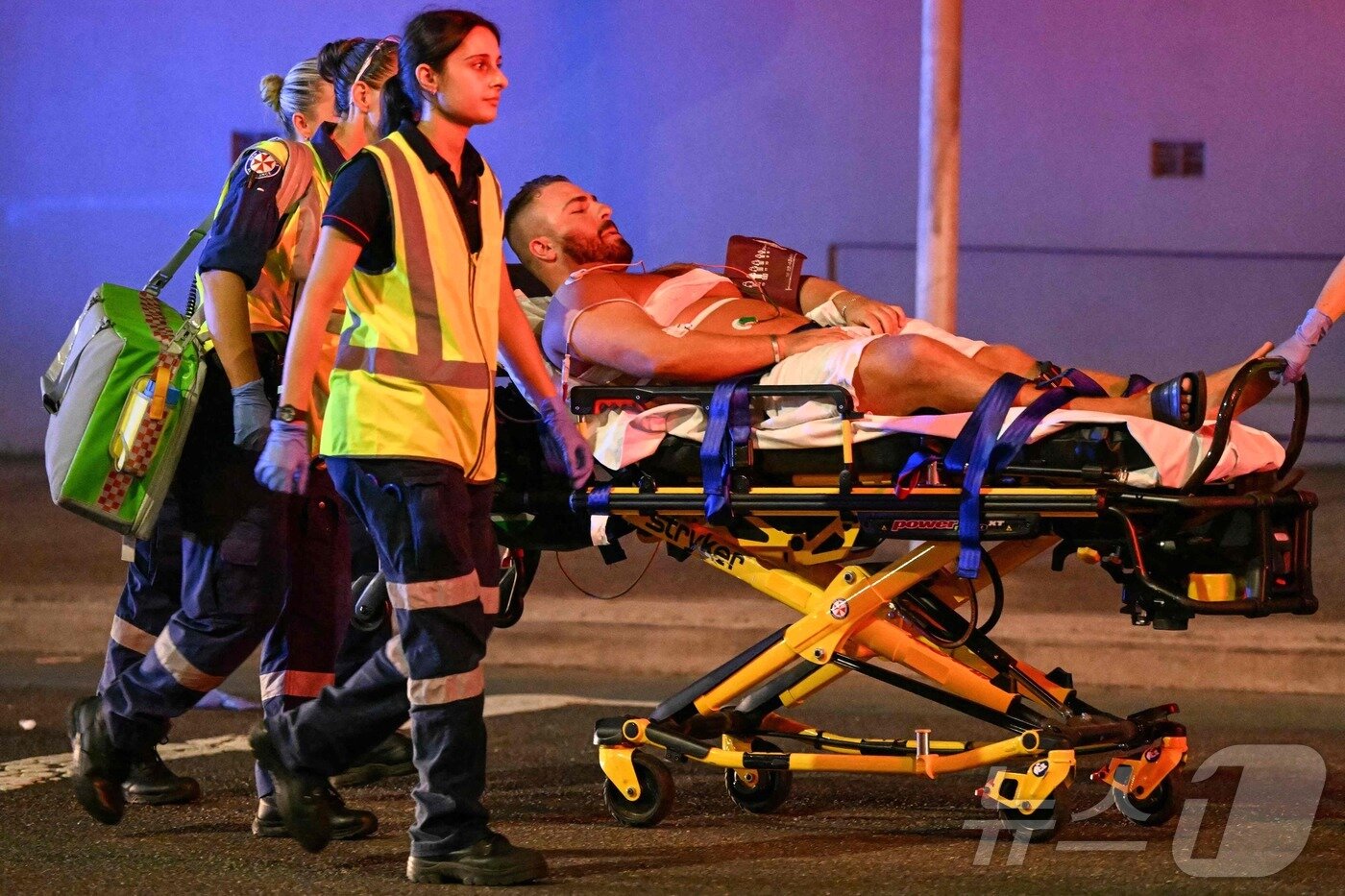 본문 이미지 - 14일(현지시간) 호주 시드니 본다이 비치에서 총격 사건이 발생한 가운데, 의료진들이 피해자들을 병원으로 후송하고 있다. 2025.12.14 ⓒ AFP=뉴스1