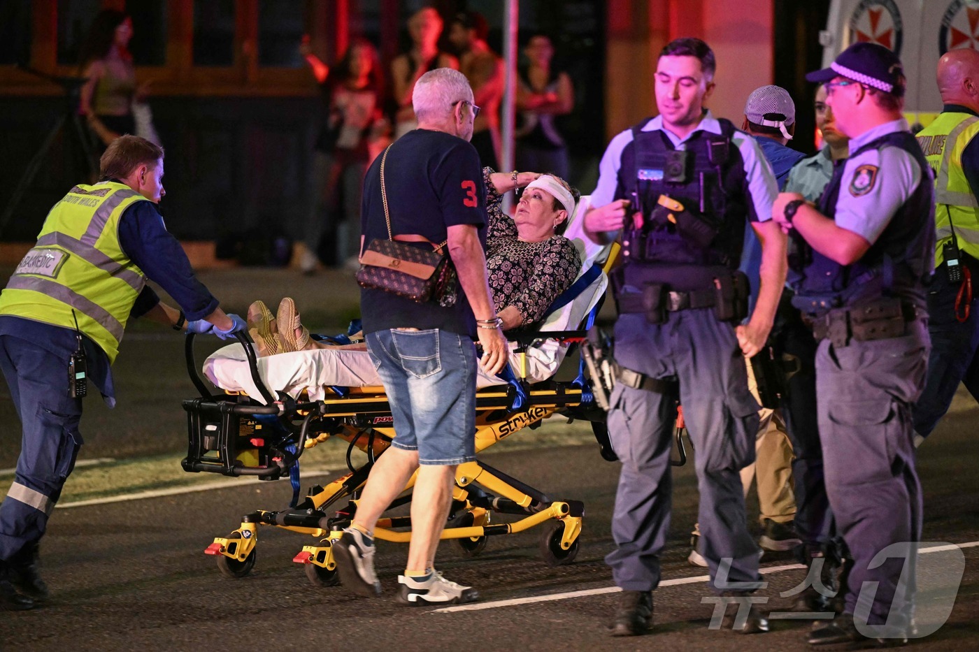 (AFP=뉴스1) = 14일(현지시간) 호주 시드니 본다이 비치에서 총격 사건이 발생한 가운데, 의료진들이 피해자들을 병원으로 후송하고 있다.ⓒ AFP=뉴스1