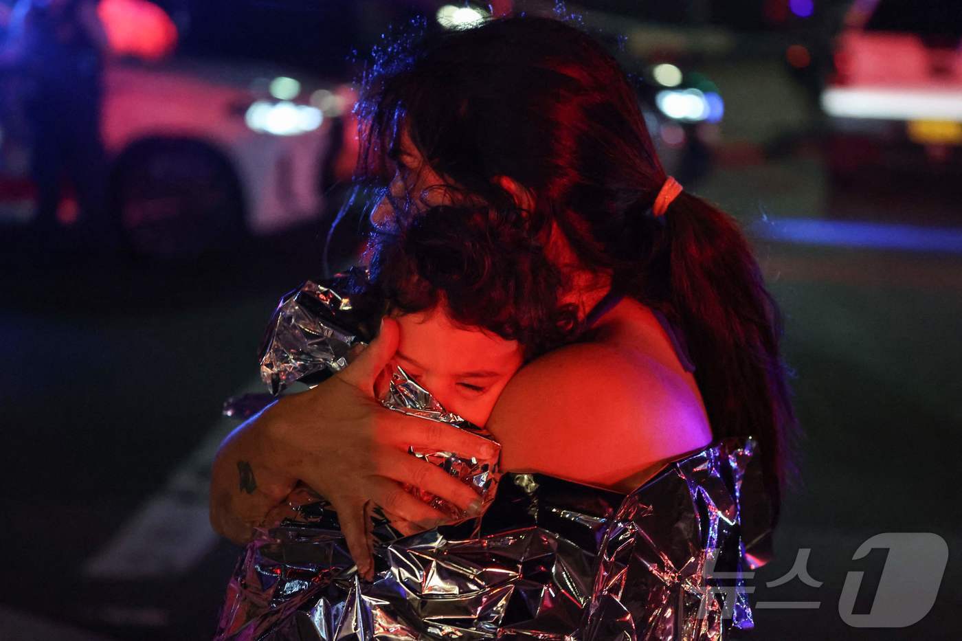 본문 이미지 - 14일(현지시간) 호주 시드니 본다이 비치에서 총격 사건이 발생한 가운데, 한 시민이 어린 아이를 안고 슬픔을 삼키고 있다. ⓒ AFP=뉴스1 ⓒ News1 김성진 기자