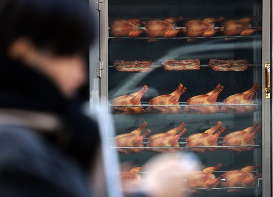 본문 이미지 - 15일 서울 시내의 한 치킨매장 앞으로 시민이 지나가고 있다. 2025.12.15/뉴스1 ⓒ News1 이호윤 기자