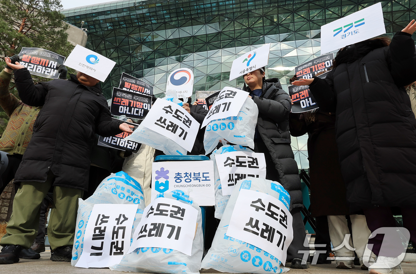 (서울=뉴스1) 이호윤 기자 = 환경운동연합 회원들이 15일 서울시청 앞에서 열린 수도권 생활폐기물 처리의 환경 부정의 문제 규탄 기자회견에서 퍼포먼스를 하고 있다. 2025.12 …