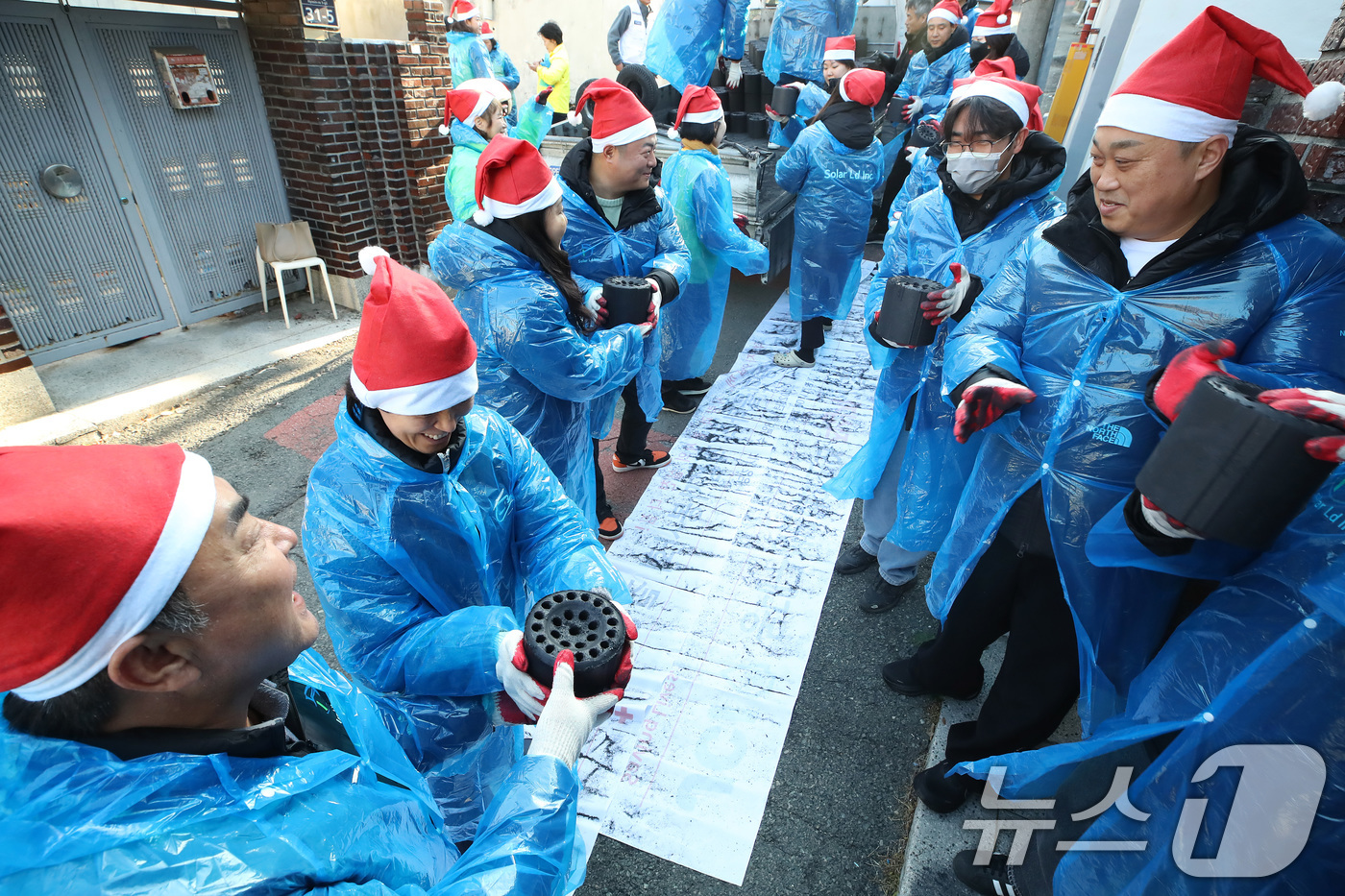 (대구=뉴스1) 공정식 기자 = 15일 오후 대구 동구 신천동 주택가에서 열린 '사랑의 연탄 나눔'에 참여한 대한적십자사 대구지사와 후원업체 봉사자들이 연탄을 주택 창고로 전달하고 …