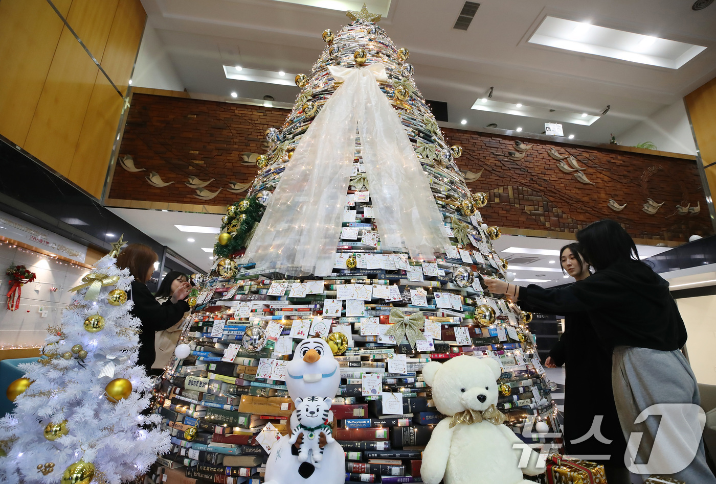 (경산=뉴스1) 공정식 기자 = 16일 오전 대구대학교 경산캠퍼스 창파도서관에서 학생들이 크리스마스를 앞두고 설치된 북(Book) 트리에 소원지를 붙이고 있다.대구대는 2008년부 …