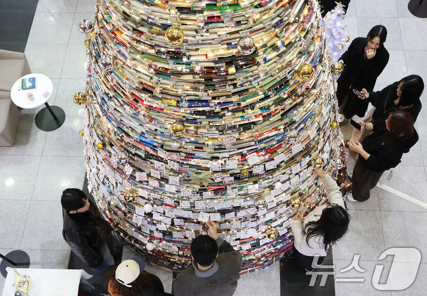 (경산=뉴스1) 공정식 기자 = 16일 오전 대구대학교 경산캠퍼스 창파도서관에서 학생들이 크리스마스를 앞두고 설치된 북(Book) 트리에 소원지를 붙이고 있다.대구대는 2008년부 …