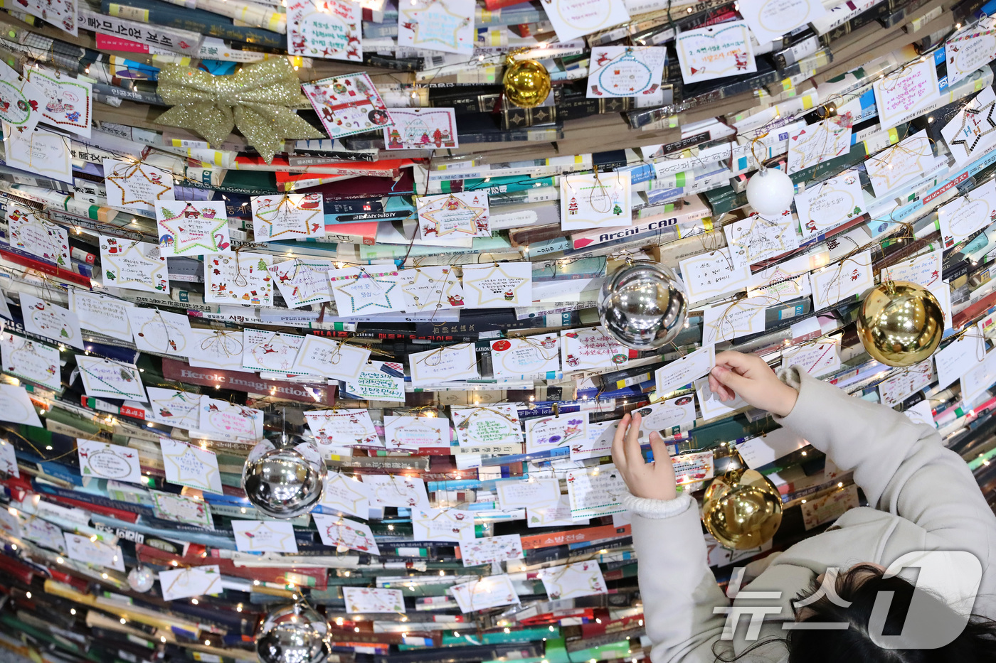 (경산=뉴스1) 공정식 기자 = 16일 오전 대구대학교 경산캠퍼스 창파도서관에서 학생들이 크리스마스를 앞두고 설치된 북(Book) 트리에 소원지를 붙이고 있다.대구대는 2008년부 …