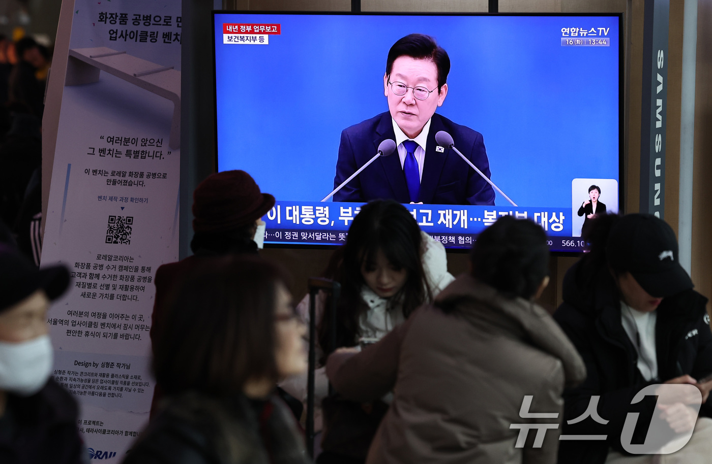 (서울=뉴스1) 구윤성 기자 = 16일 오후 서울 용산구 서울역 대합실 텔레비전을 통해 이재명 대통령의 보건복지부 등에 대한 업무보고 영상이 생중계되고 있다.  2025.12.16 …