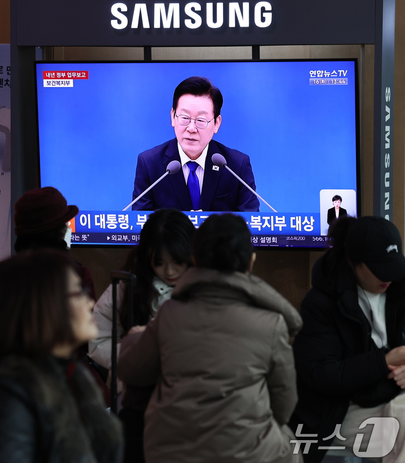 (서울=뉴스1) 구윤성 기자 = 16일 오후 서울 용산구 서울역 대합실 텔레비전을 통해 이재명 대통령의 보건복지부 등에 대한 업무보고 영상이 생중계되고 있다.  2025.12.16 …