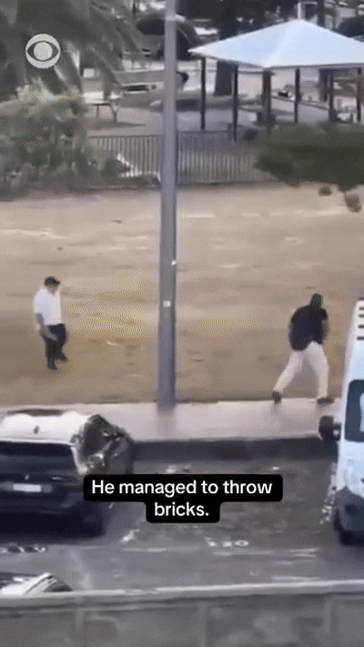 본문 이미지 - 지난 14일 호주 시드니 테러 당시 시리아 출신 무슬림인 과일가게 주인 아흐메드가 총격범으로부터 총을 빼앗자 뒤따라 벽돌을 던져 총격범을 저지하는 루벤 모리슨의 모습 (출처=CBS 뉴스 페이스북)