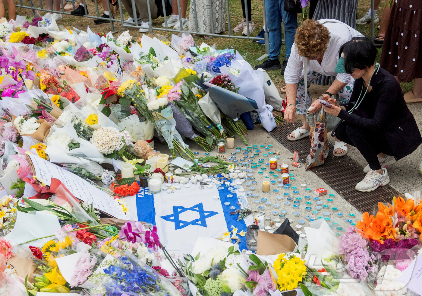 (시드니 로이터=뉴스1) 강민경 기자 = 호주 시드니 본다이 비치 인근 하누카 축제 현장에서 발생한 총기난사 사건 이후 방문객들이 16일 현장에 헌화하며 추모하고 있다. 2025. …
