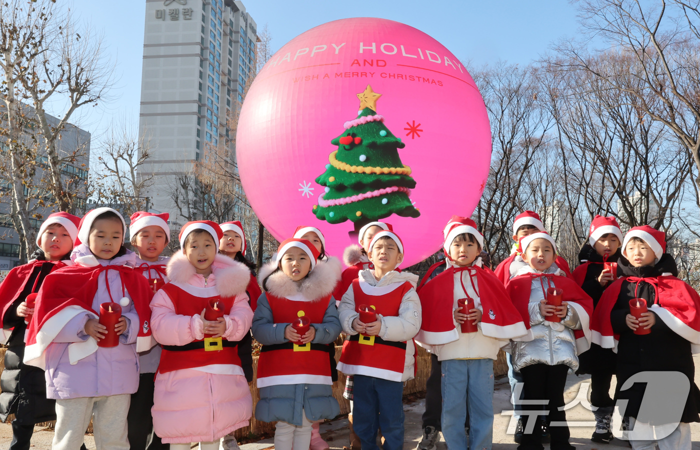 (서울=뉴스1) 장수영 기자 = 산타 복장을 차려입은 송파구청 어린이집 아이들이 18일 오전 서울 송파구 석촌호수 더 스피어에서 크리스마스 캐럴을 부르고 있다.송파구는 연말연시를 …