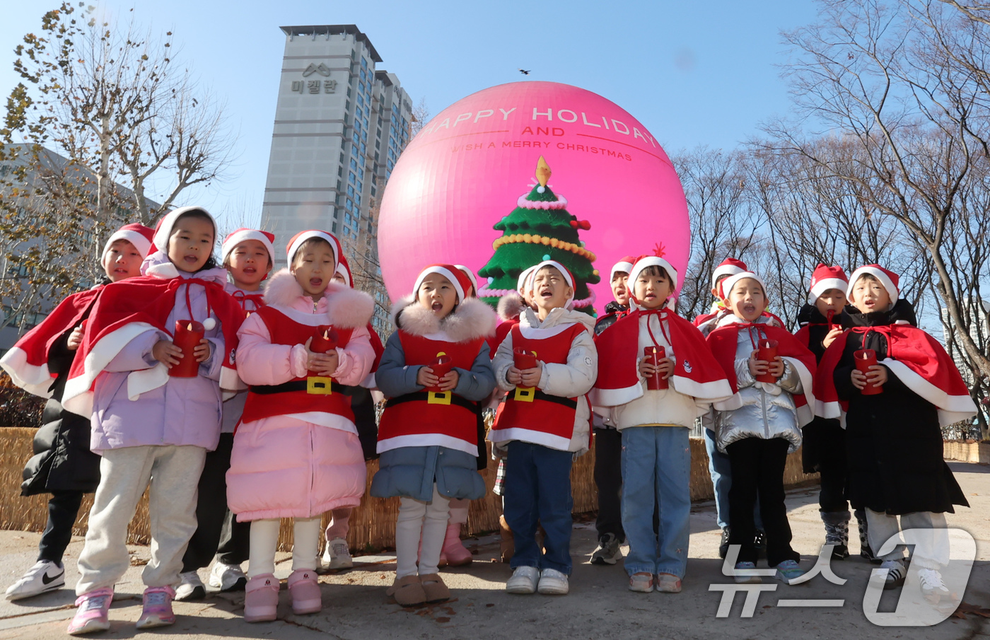 (서울=뉴스1) 장수영 기자 = 산타 복장을 차려입은 송파구청 어린이집 아이들이 18일 오전 서울 송파구 석촌호수 더 스피어에서 크리스마스 캐럴을 부르고 있다.송파구는 연말연시를 …