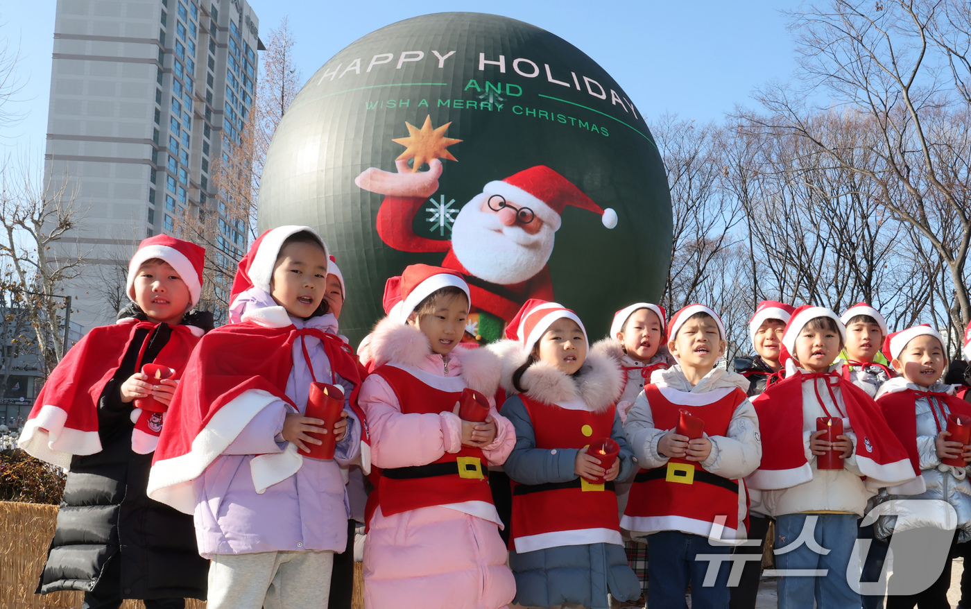 (서울=뉴스1) 장수영 기자 = 산타 복장을 차려입은 송파구청 어린이집 아이들이 18일 오전 서울 송파구 석촌호수 더 스피어에서 크리스마스 캐럴을 부르고 있다.송파구는 연말연시를 …