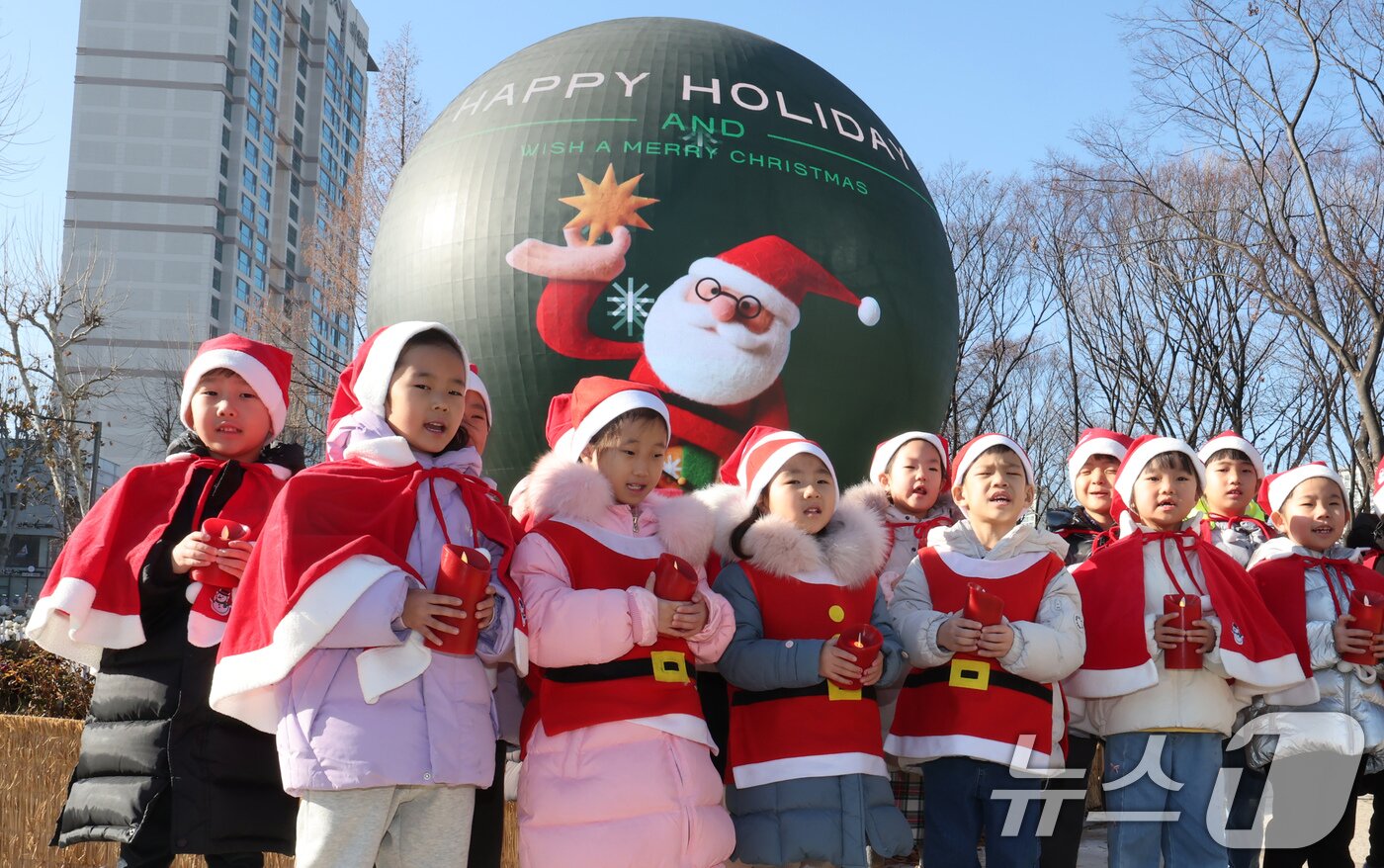 본문 이미지 - 산타 복장을 차려입은 송파구청 어린이집 아이들이 18일 오전 서울 송파구 석촌호수 더 스피어에서 크리스마스 캐럴을 부르고 있다.  2025.12.18/뉴스1 ⓒ News1 장수영 기자
