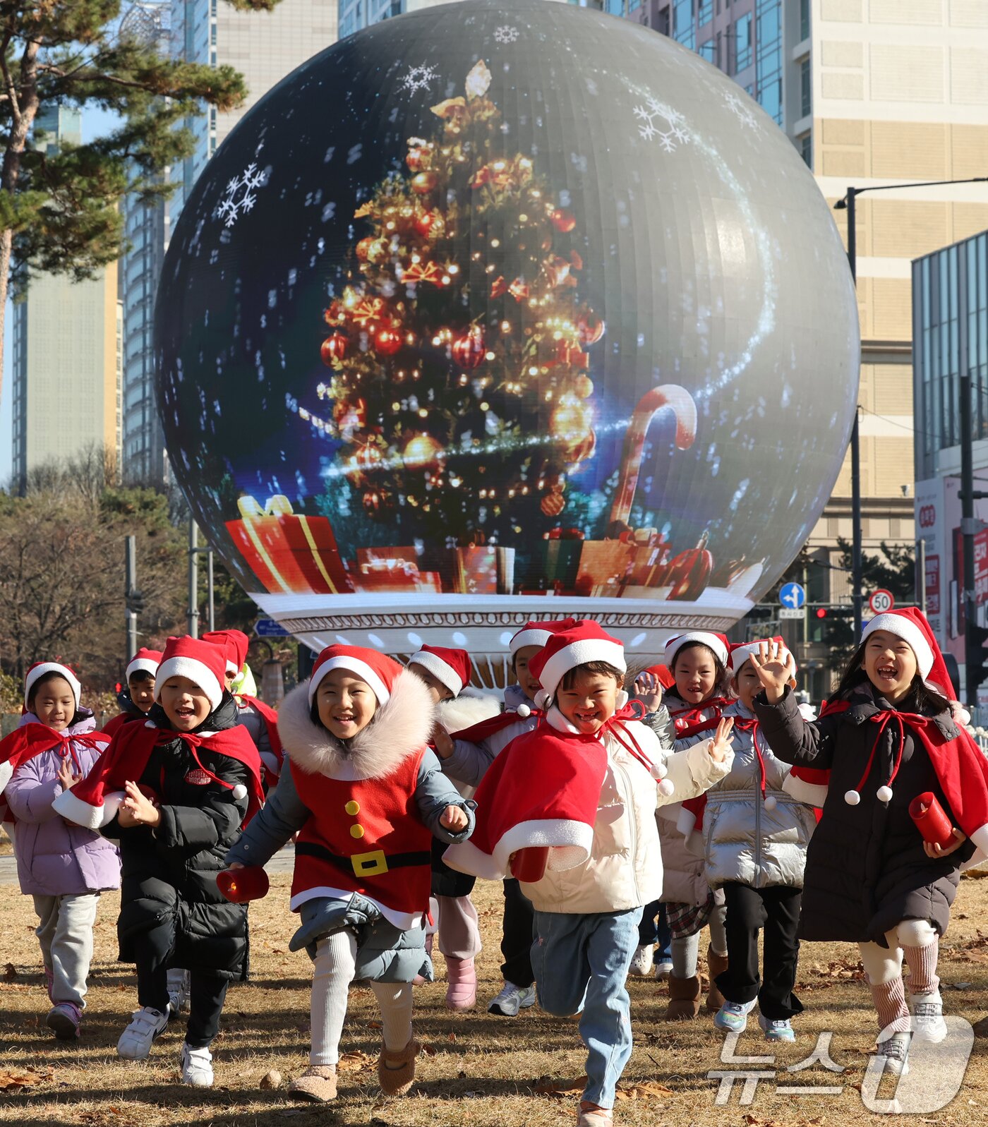 본문 이미지 - 산타 복장을 차려입은 송파구청 어린이집 아이들이 18일 오전 서울 송파구 석촌호수 더 스피어에서 놀이를 하고 있다.  2025.12.18/뉴스1 ⓒ News1 장수영 기자