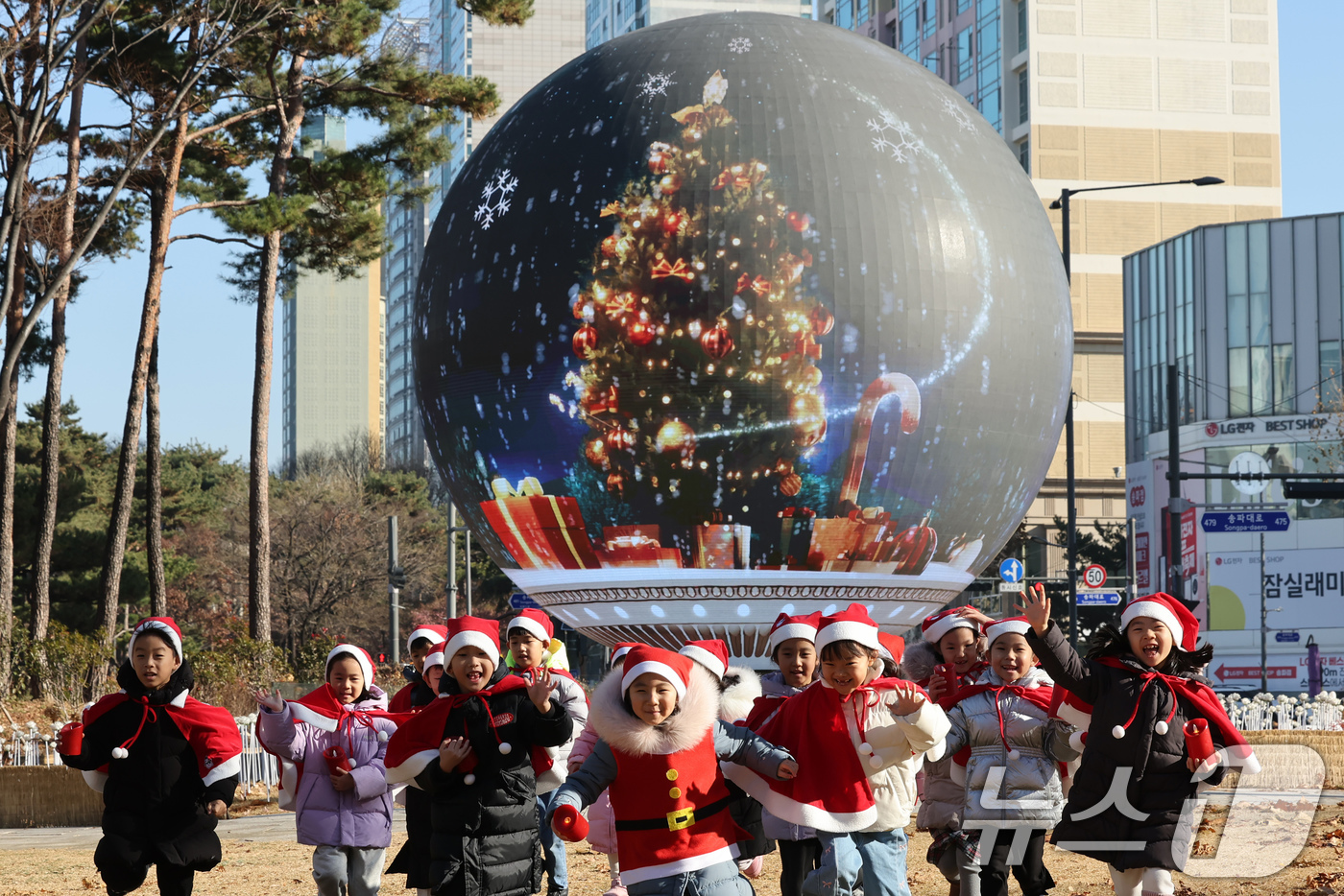 (서울=뉴스1) 장수영 기자 = 산타 복장을 차려입은 송파구청 어린이집 아이들이 18일 오전 서울 송파구 석촌호수 더 스피어에서 놀이를 하고 있다.송파구는 연말연시를 맞아 더 스피 …
