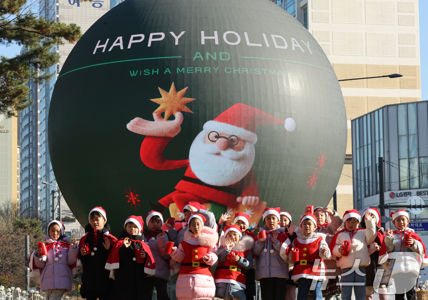 (서울=뉴스1) 장수영 기자 = 산타 복장을 차려입은 송파구청 어린이집 아이들이 18일 오전 서울 송파구 석촌호수 더 스피어에서 손을 흔들고 있다.송파구는 연말연시를 맞아 더 스피 …