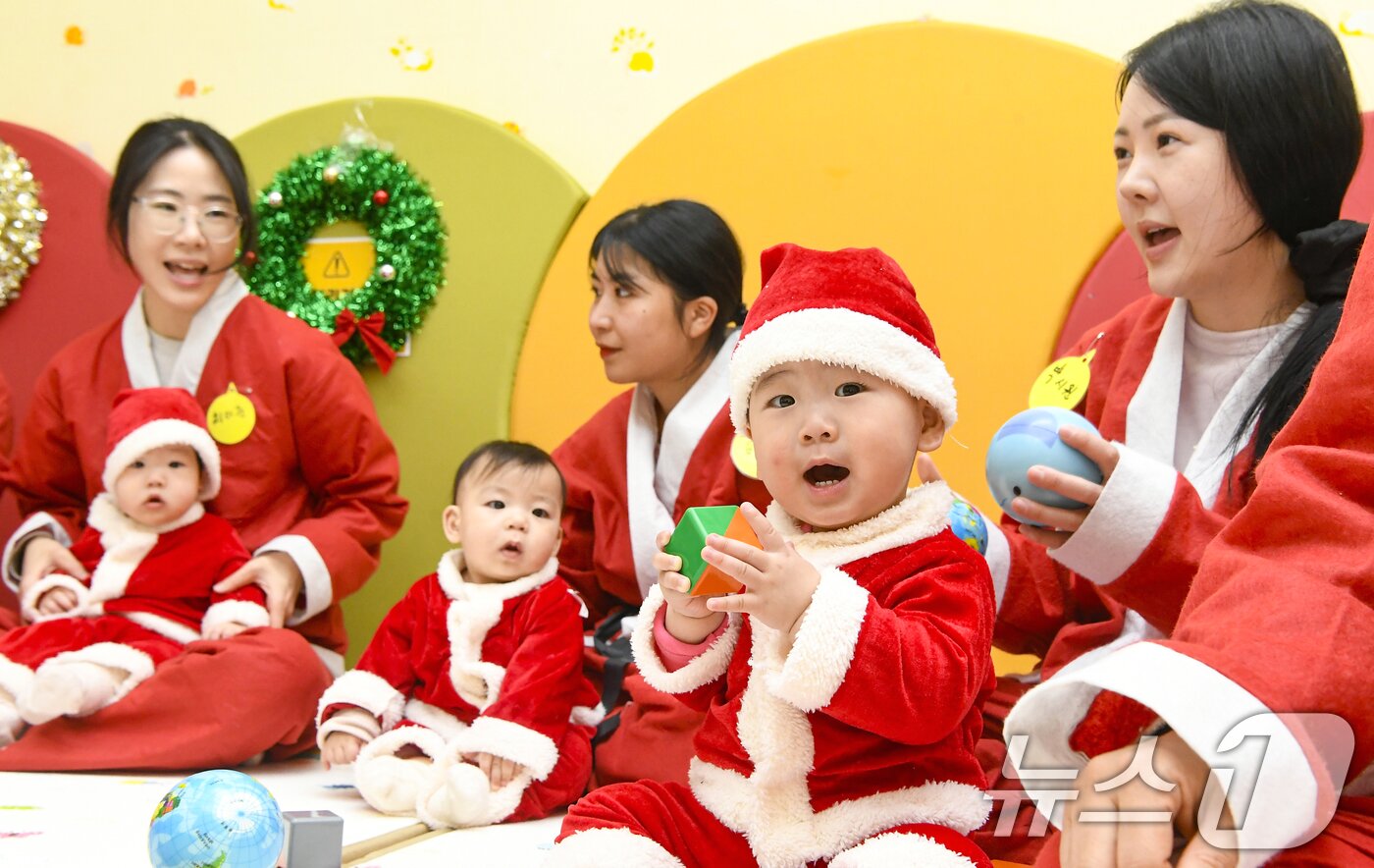 본문 이미지 - 크리스마스를 일주일 앞둔 18일 경기 광주시 능평도서관에서 산타 복장을 입은 엄마와 아기들이 놀이를 하고 있다. (공동취재) 2025.12.18/뉴스1 ⓒ News1 김영운 기자