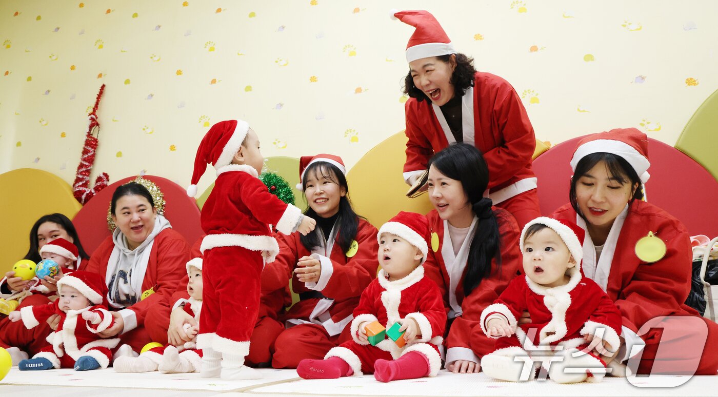본문 이미지 - 크리스마스를 일주일 앞둔 18일 경기 광주시 능평도서관에서 산타 복장을 입은 엄마와 아기들이 놀이를 하고 있다. 2025.12.18/뉴스1 ⓒ News1 김영운 기자