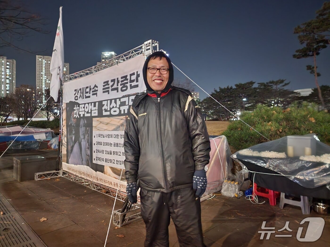 본문 이미지 - 농성 사흘차인 지난 11일 오후 10시가 넘은 시각. 김헌주 경북북부이주노동자센터 소장이 농성장 앞에 서 있다. 그는 "소장보다는 평소 아저씨라고 불리는 것이 더 편하다"고 말했다. 농성장 옆에는 고 뚜안의 임시 분향소가 차려져 있다.2025.12.11/ⓒ 뉴스1 권진영 기자