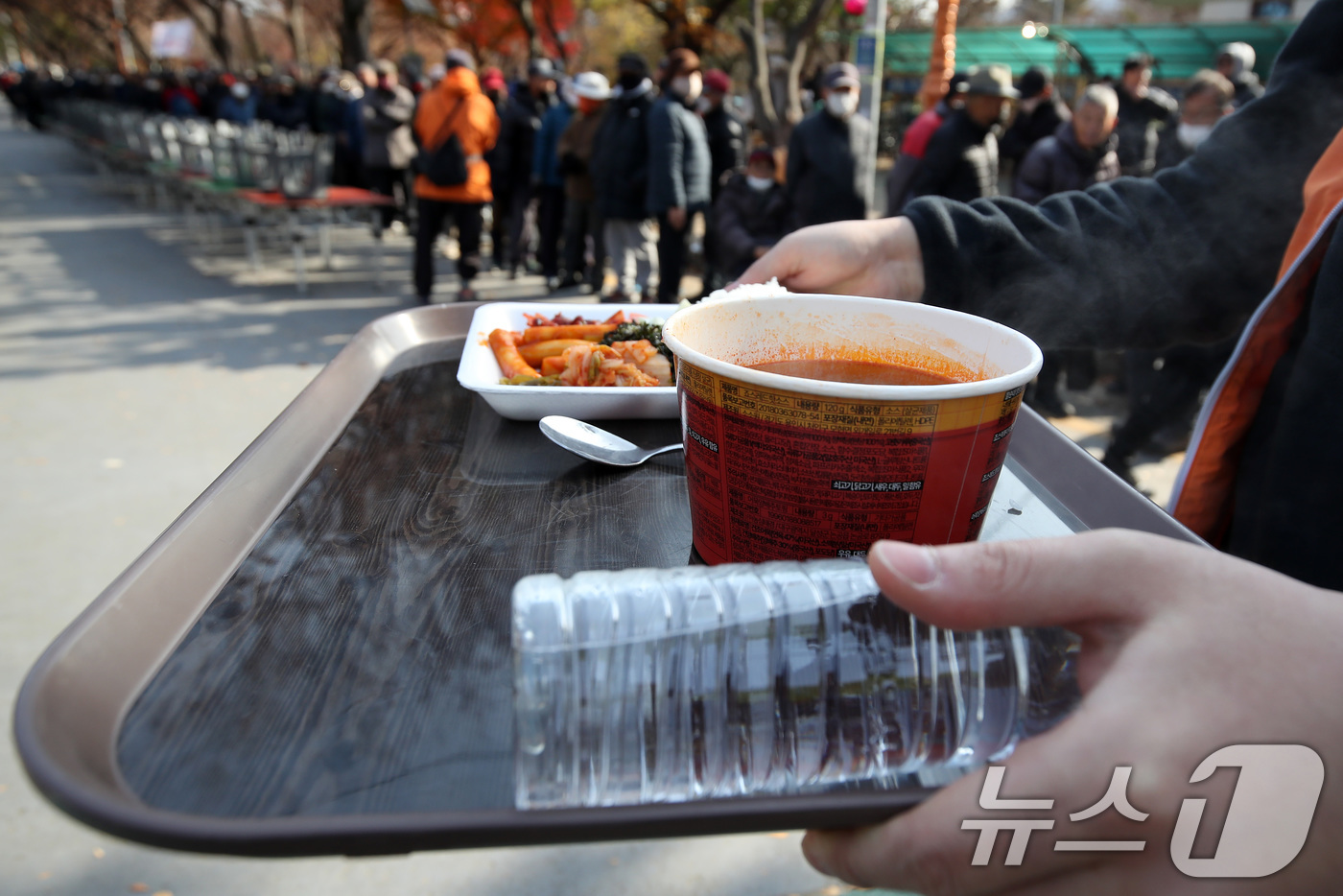 (대구=뉴스1) 공정식 기자 = 초겨울 추위가 찾아온 2일 오전 대구 달서구 두류공원 사랑해밥차 무료급식소에서 점심 배식 식판을 받은 사람들이 식사할 곳으로 이동하고 있다. 202 …