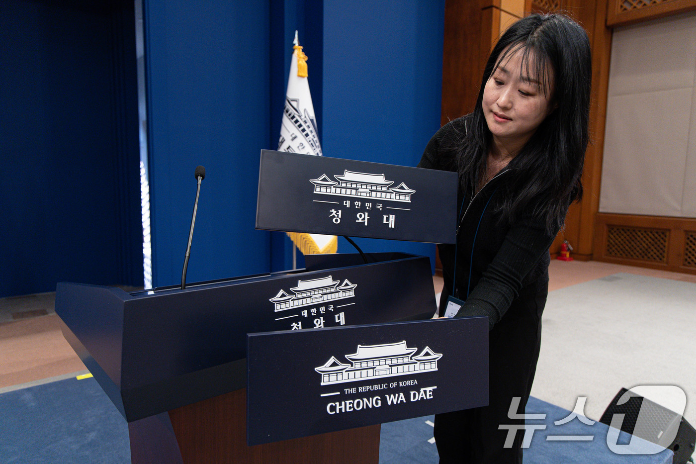 (서울=뉴스1) 이재명 기자 = 대통령실이 청와대 순차 이전을 진행 중인 21일 청와대 춘추관 브리핑룸에서 직원이 탈부착 업무표장을 설치하고 있다. 2025.12.21/뉴스1