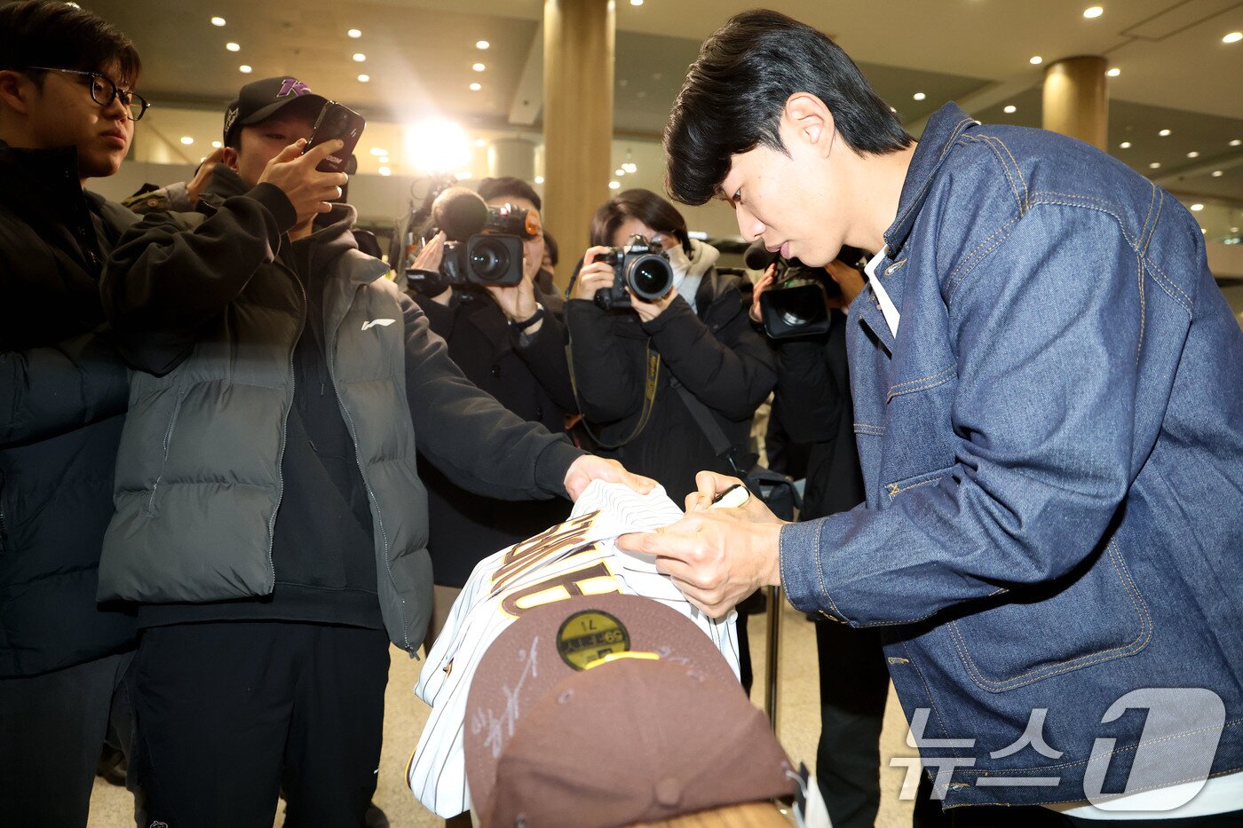 본문 이미지 - 미국프로야구 메이저리그(MLB) 샌디에이고 파드리스와 4년 계약을 맺은 송성문이 23일 오전 인천국제공항을 통해 귀국해 한 팬에게 사인을 해주고 있다. 2025.12.23/뉴스1 ⓒ News1 이광호 기자