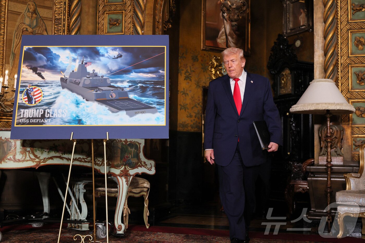 본문 이미지 - 22일(현지시간) 도널드 트럼프 미국 대통령이 플로리다주 팜비치 마러라고에서 해군의 신형 '황금 함대'(Golden Fleet) 관련 '트럼프급' 전투함 USS 데이펀트의 조감도를 지나고 있다. 2025.12.22. ⓒ 로이터=뉴스1