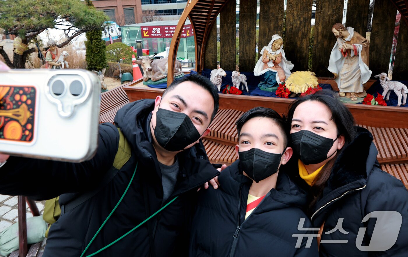 본문 이미지 - 크리스마스 이브를 하루 앞둔 23일 서울 중구 명동대성당 앞에 설치된 성탄 구유에서 외국인 관광객들이 기념사진을 찍고 있다. 2025.12.23/뉴스1 ⓒ News1 이호윤 기자