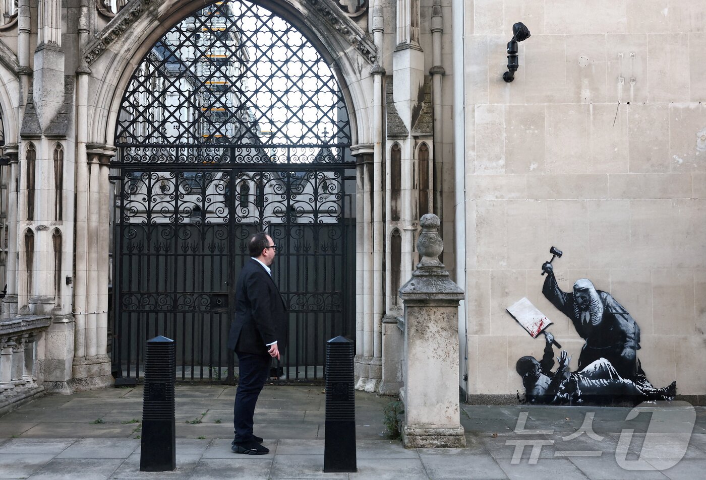 본문 이미지 - 2025년 9월 9일, 영국 런던 왕립법원(Royal Courts of Justice) 건물에 등장한 익명의 예술가 뱅크시의 새로운 벽화를 한 행인이 바라보고 있다. ⓒ 로이터=뉴스1