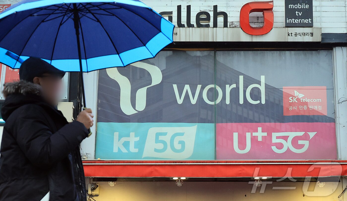 본문 이미지 -  서울의 한 휴대폰 매장 앞으로 시민이 지나가고 있다. 2025.12.23 ⓒ 뉴스1 김진환 기자