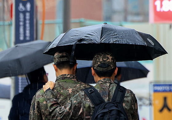우산 함께 쓴 군인들