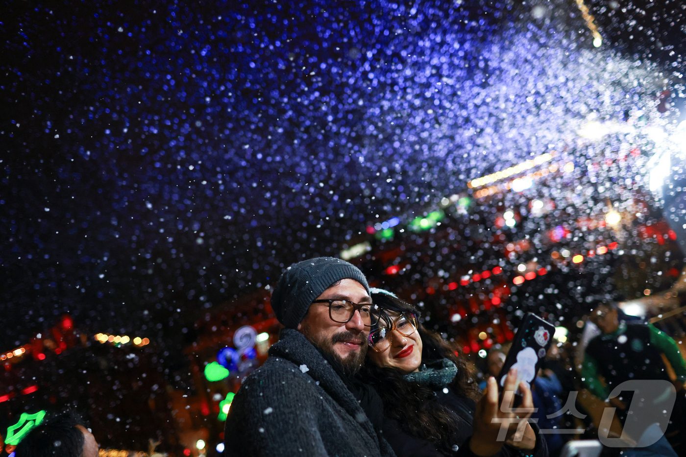 (멕시코시티 로이터=뉴스1) 이정환 기자 = 22일(현지시간) 멕시코의 수도 멕시코시티 소칼로 광장에서 열린 크리스마스 축제가 비눗방울로 눈을 연출하자 한 커플이 셀카를 찍고 있다 …