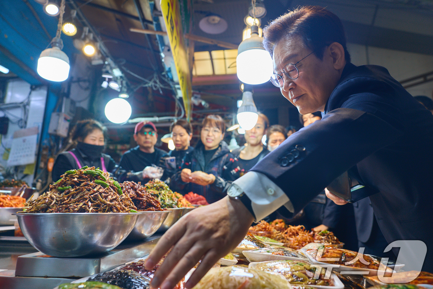 (서울=뉴스1) = 이재명 대통령이 23일 부산 진구 부전시장을 찾아 반찬을 고르고 있다. (대통령실 제공. 재판매 및 DB 금지) 2025.12.23/뉴스1