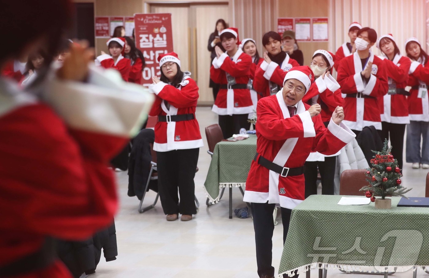 (서울=뉴스1) = 서강석 송파구청장이 23일 구청 대강당에서 열린 잠실산타이즈 커밍 출정식에서 산타 복장을 한 봉사자들과 노래를 부르며 율동을 하고 있다.송파구는 크리스마스를 앞 …